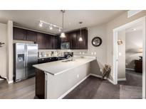 Modern kitchen featuring stainless steel appliances, dark wood cabinets and a quartz countertop bar at 9258 Rockhurst St # 303, Highlands Ranch, CO 80129