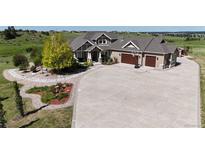 Sprawling home featuring a circular driveway, and a well-manicured lawn with mature trees and landscaping at 960 Promontory Cir, Elizabeth, CO 80107
