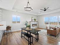 Bright open-concept dining area boasts wood floors, modern lighting, fireplace and views of the surrounding landscape at 61800 E 32Nd Ct, Strasburg, CO 80136
