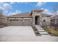 Inviting two-story home with a three-car garage, stone accents, and well-manicured lawn at 8815 S Tibet Ct, Aurora, CO 80016