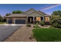 Charming home with a stone and siding exterior, manicured lawn, and a spacious three-car garage at 7126 E 162Nd Ct, Brighton, CO 80602
