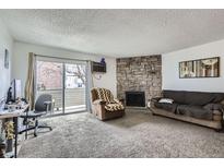 Comfortable living room with stone fireplace and sliding glass door to private balcony, creating a cozy space at 10150 E Virginia Ave # 5-107, Denver, CO 80247