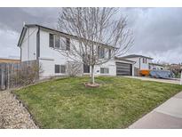 Charming two-story home with a well-manicured lawn and attached garage under a cloudy sky at 6592 S Cody Way, Littleton, CO 80123