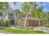 Charming home exterior with stone accents, a manicured lawn, and lush landscaping at 1540 W Briarwood Ave, Littleton, CO 80120