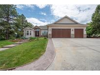 Charming stucco home with a three-car garage, mature landscaping, and a stone pathway leading to the front door at 1030 Timbercrest Dr, Castle Pines, CO 80108