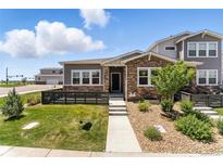 Charming home featuring a stone facade, well-maintained lawn, and inviting entrance in a vibrant community at 15501 E 112Th Ave # 6F, Commerce City, CO 80022