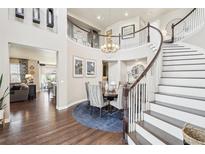 Elegant foyer with a sweeping staircase, hardwood floors, and a view into the formal dining room at 25548 E Fair Dr, Aurora, CO 80016