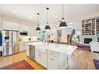 Bright kitchen with stainless steel appliances, white cabinets, and large island with pendant lighting at 1455 Flowers Ct, Erie, CO 80516