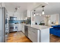 Bright kitchen features stainless steel appliances, white cabinets, modern backsplash, and an island with a marble countertop at 1090 N Lafayette St # 503, Denver, CO 80218