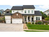 Charming two-story home featuring a manicured lawn, stone accents, and a three-car garage at 23421 E Rockinghorse Pkwy, Aurora, CO 80016