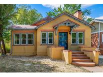 Charming stucco home with colorful trim, an inviting front porch and beautiful yard at 1401 Ash St, Denver, CO 80220