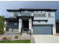 Charming two-story home featuring a covered porch, two-car garage, and stylish blue siding at 767 Raindance St, Erie, CO 80516