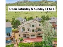 A stunning two-story home featuring a wrap-around deck and lush landscaping, nestled in a picturesque mountain setting at 165 Washington St, Golden, CO 80403