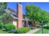 Inviting home exterior featuring a brick chimney, mature trees, and well-maintained landscaping for a warm and welcoming curb appeal at 11884 Elk Head Range Rd, Littleton, CO 80127