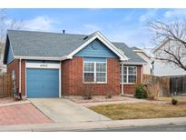 Charming brick home featuring a blue garage door, gray roof, and a well-maintained front lawn at 4922 Altura St, Denver, CO 80239
