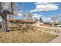 Charming single-story brick home featuring a well-maintained lawn, mature tree, and attached one car garage at 7049 W 74Th Ave, Arvada, CO 80003