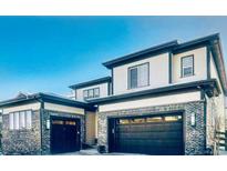 View of the home's exterior with brick accents and two-car garage doors at 6506 Barnstead Dr, Castle Pines, CO 80108