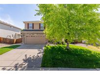 Charming two-story home featuring a well-manicured lawn, mature tree, and a two-car garage with a brick accent at 13180 Jasmine St, Thornton, CO 80602