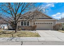 Tan home with a two car garage, brick trim and drought resistant landscaping at 1853 S Marshall Cir, Lakewood, CO 80232
