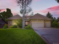 Charming home featuring a three car garage, brick accents, manicured lawn, and mature trees at 15224 W 73Rd Ave, Arvada, CO 80007