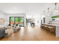 Bright, open-concept living space with light hardwood floors seamlessly connecting living, dining, and kitchen areas at 1241 S Garfield St, Denver, CO 80210