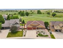 Expansive aerial view of a well-maintained home with a three-car garage, landscaped yard, and open green space behind the home at 1100 Columbine Way, Erie, CO 80516