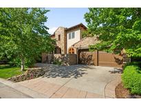 Attractive stone-clad home with a spacious driveway, beautiful landscaping, and a three-car garage at 9151 E Harvard Ave, Denver, CO 80231