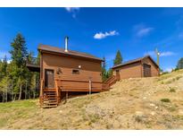 Inviting mountain home featuring wood siding, a charming deck, and separate garage at 33606 Gap Rd, Golden, CO 80403
