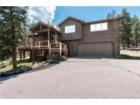 Two-story home with a two-car garage, wood exterior and nicely maintained front yard at 32663 Donna Dr, Conifer, CO 80433