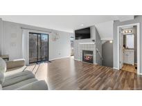 Bright living room with wood floors, fireplace, TV, sliding glass door, and access to an adjacent bathroom at 1379 S Idalia St # C, Aurora, CO 80017