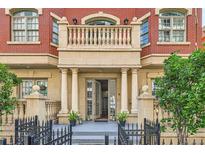 Elegant brick townhome with a stone balcony and entrance framed by columns and wrought iron fence at 1950 N Logan St # 108, Denver, CO 80203