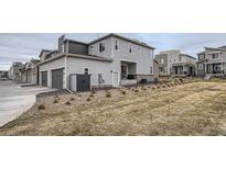 View of the home's rear facade with a two-car garage and low maintenance landscaping at 12345 Festival Ln, Thornton, CO 80241
