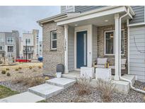 Inviting front porch with blue door, brick accents, and patio seating on well-maintained property at 12345 Festival Ln, Thornton, CO 80241