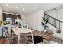 Bright living space with modern table, stylish clear chairs, hardwood floors, and sleek staircase at 2036 S Vance Way, Lakewood, CO 80227