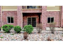 Brick condo exterior with river rock landscaping, bushes, balcony and entrance at 1144 Rockhurst Dr # 105, Highlands Ranch, CO 80129