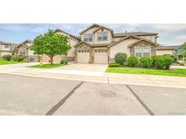 Inviting townhome showcases stone accents, a lush green lawn, and an attached two-car garage at 23070 York Ave, Parker, CO 80138