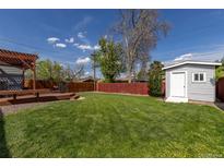 Expansive backyard featuring lush green grass, a wooden deck, and a storage shed for outdoor enjoyment at 7286 Wolff St, Westminster, CO 80030