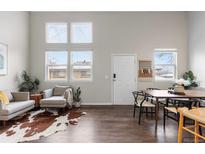 Open-plan living room with high ceilings, large windows, modern furnishings, and wood floors at 6450 W 44Th Pl # B3, Wheat Ridge, CO 80033
