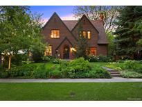 Charming brick two-story home with lush landscaping and mature trees providing curb appeal at 1960 Hudson St, Denver, CO 80220