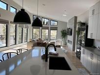 Bright kitchen with modern black fixtures, island, and seamless views to the living room and outdoor landscape at 7125 Skygazer St, Castle Pines, CO 80108