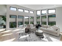Bright living room features large windows, light wood floors, and a comfortable seating area at 7125 Skygazer St, Castle Pines, CO 80108