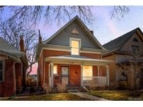 Charming two-story red brick home with a covered porch and classic architectural details at dusk at 2146 Federal Blvd, Denver, CO 80211