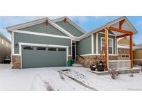Gray two-story house with a large garage and covered porch, snow on the ground at 11494 Colony Loop, Parker, CO 80138