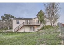 Charming two-story home featuring a wooden deck, grassy yard, and inviting entrance at 1062 Pinon Ln, Elizabeth, CO 80107