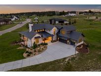 Stunning aerial view of stone home with a three-car garage and basketball hoop at dusk at 2442 Fox View Trl, Franktown, CO 80116