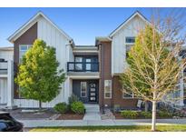 Charming two-story townhouse with a modern exterior, balcony, and well-maintained landscaping at 10165 E 59Th Ave, Denver, CO 80238