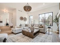 Spacious living room with large windows, neutral-toned furniture, and stylish light fixtures at 3649 W 21St Ave, Denver, CO 80211
