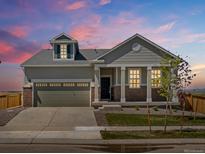 Charming single-Gathering home with a two-car garage, inviting front porch and manicured lawn at dusk at 9069 Pitkin St, Commerce City, CO 80022