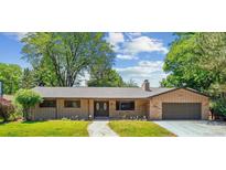 Charming ranch-style home with stone accents, manicured lawn, mature trees, and inviting walkway at 6330 E Vassar Ave, Denver, CO 80222