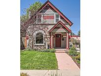 Charming two-story home featuring a well-manicured lawn, mature trees, and a welcoming red-trimmed entrance at 3047 Osceola St, Denver, CO 80212